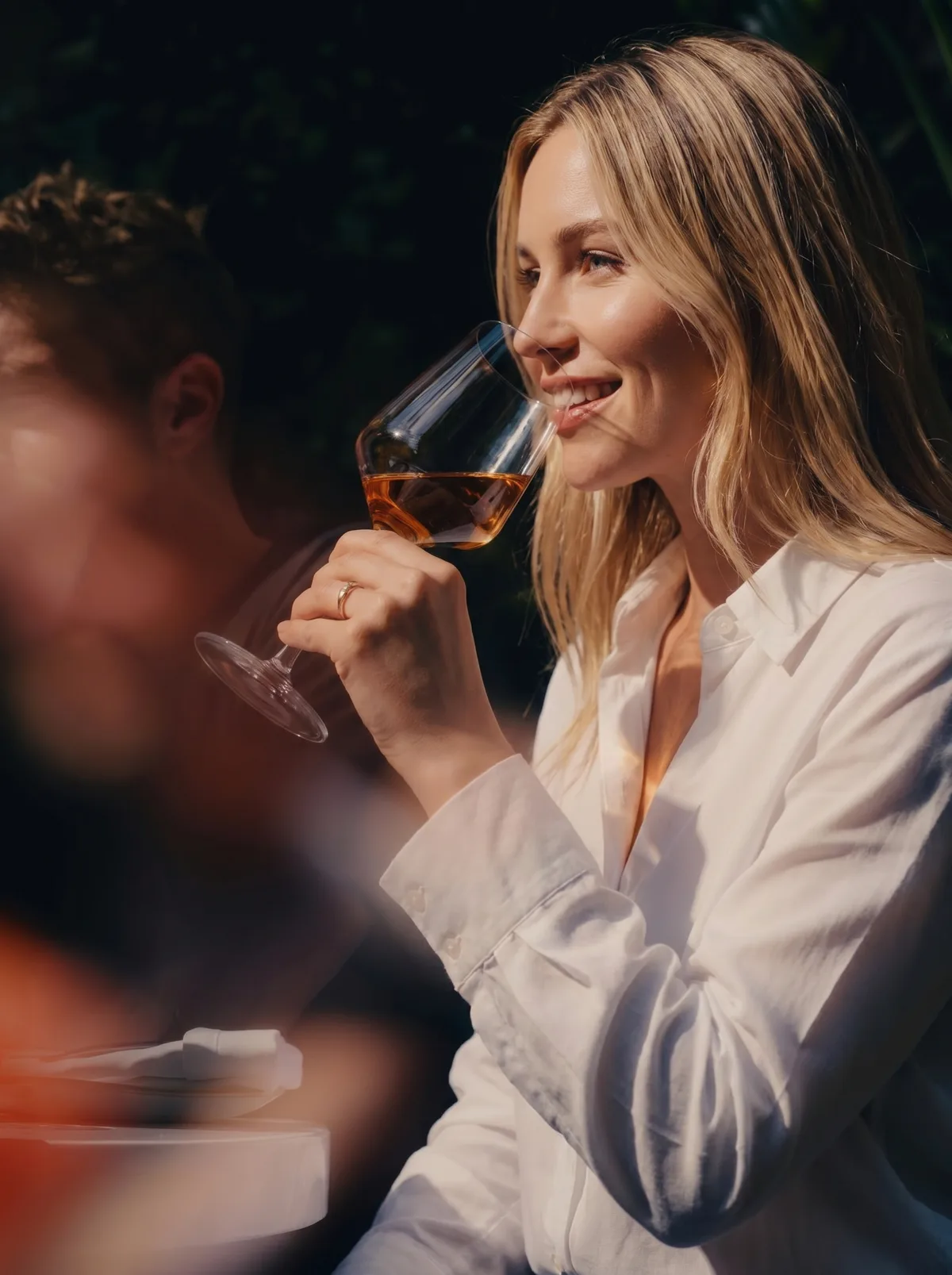 A guest enjoying a glass of white wine at an evening event